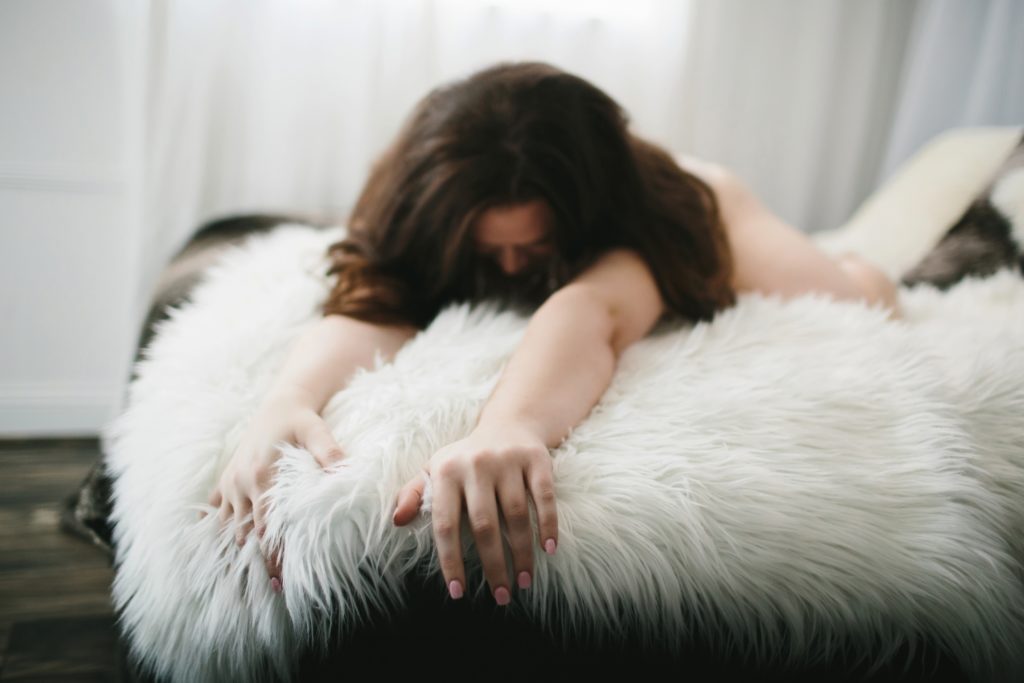 Brunette Woman on fur covered bed, Brunette Woman in cream lingerie and pearls on floor next to teal couch, Boudoir Photography by Lindsay Hite