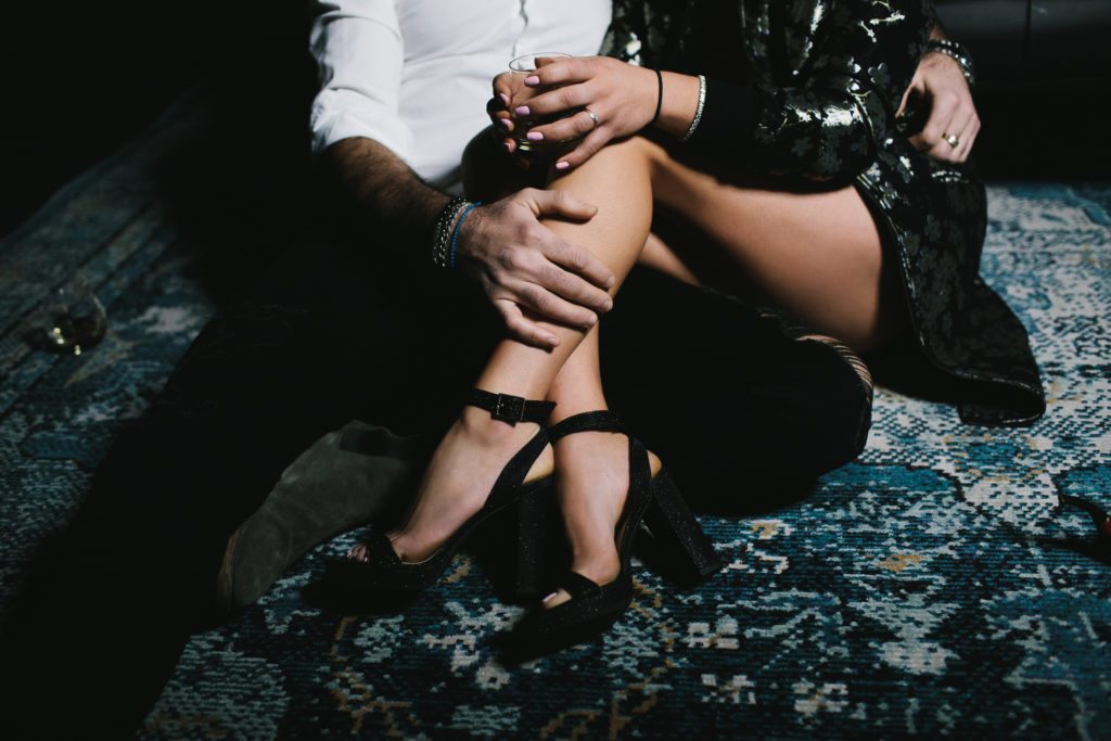 couple's boudoir portrait; woman in black heals, man in white button shirt holding her leg; women's empowerment photography by Lindsay Hite