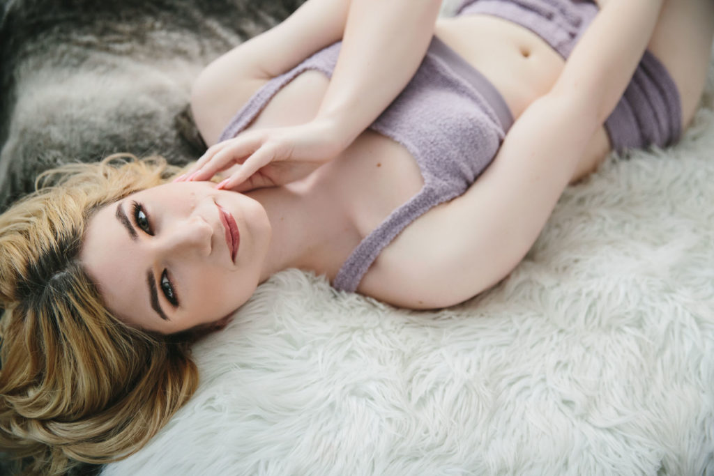 Woman in lilac lingerie on white bed, through the lens of beauty, boudoir photography by Lindsay Hite