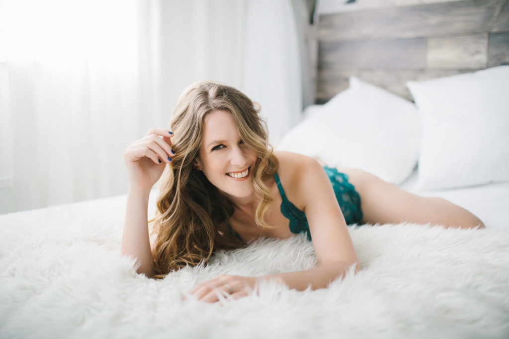 woman in teal body suit on fur-lined bed; boudoir photography by Lindsay Hite