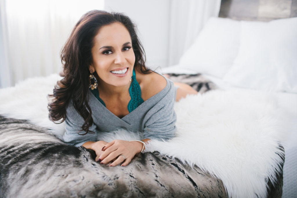 woman in oversized sweater on fur lined bed; photography by Lindsay Hite