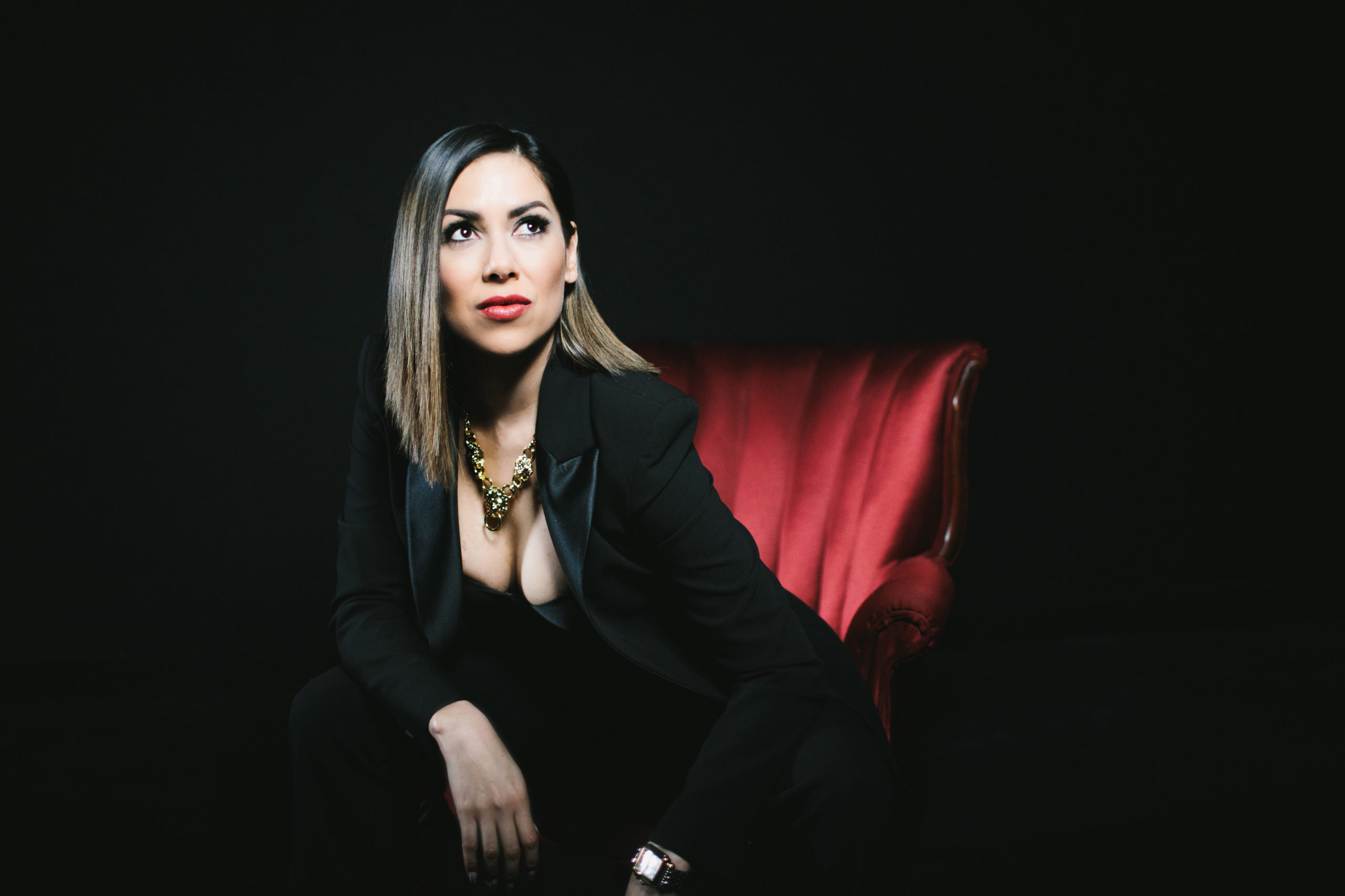 Woman in suit on red chair; how to create time for a boudoir session; photography by Lindsay Hite