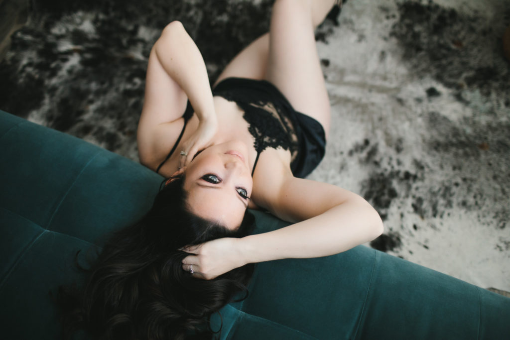 woman in black lingere siting on the floor against teal sofa, photography by Lindsay Hite