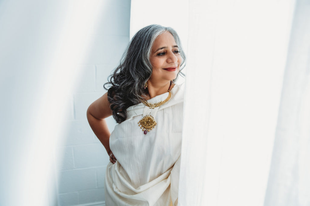 Boston-Area Luxury Photography Studio for women of all ages, older woman in white Sari inspired gown with white background and white curtains