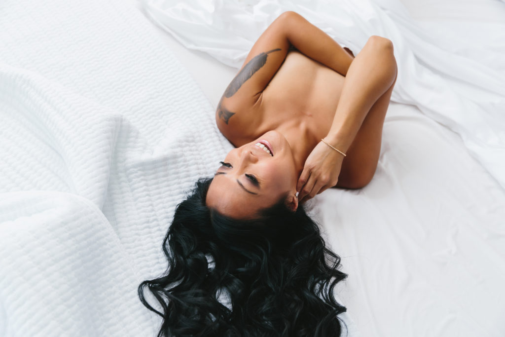 Asian woman between crisp white sheets, boudoir photography by Lindsay Hite