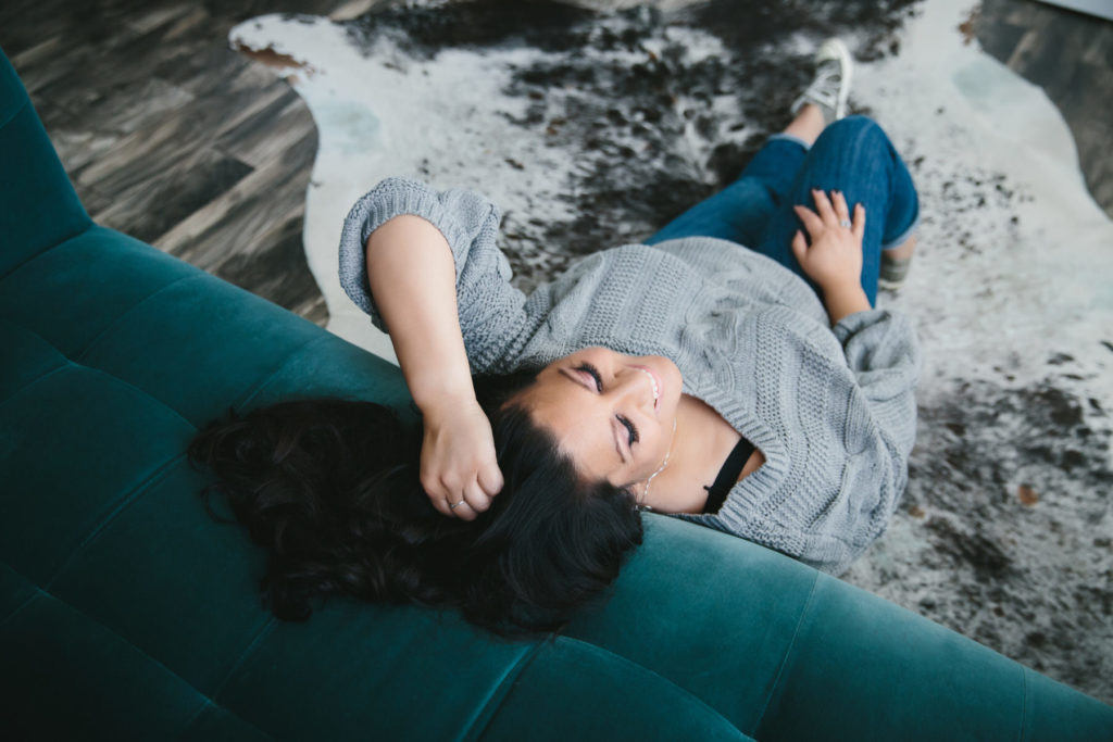 Middle Eastern woman in gray sweater and jeans next to teal sofa, Boudoir for Life Coaches by Lindsay Hite