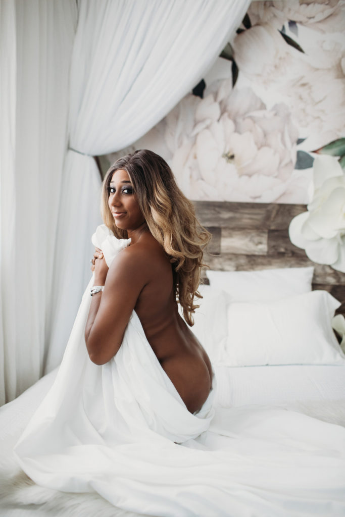 African American woman posing between white sheets; boudoir photography by Lindsay Hite