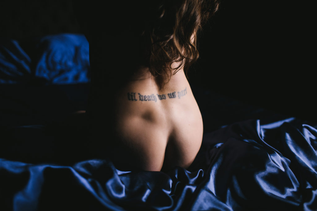 Woman nude between navy satin colored sheets; empowerment photography by Lindsay Hite
