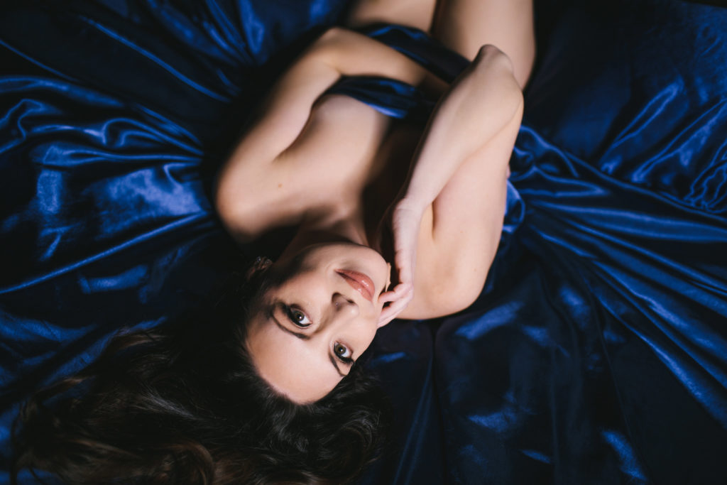 Woman nude between navy satin colored sheets; empowerment photography by Lindsay Hite