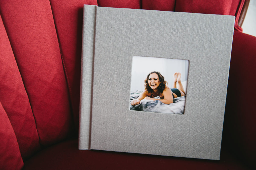 Grey linen album cover with image of woman on the front.  Album sitting on Red chair. Photography by Lindsay Hite