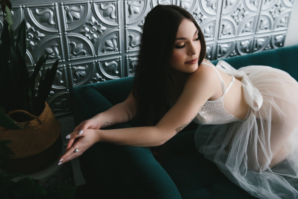brunette in bridal lingerie sitting on teal sofa, bridal boudoir photography by Lindsay Hite
