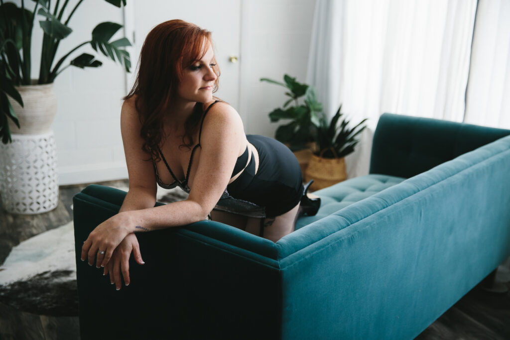 Woman in black body suit on teal sofa, Bright Boudoir Photography Scenes by Lindsay Hite