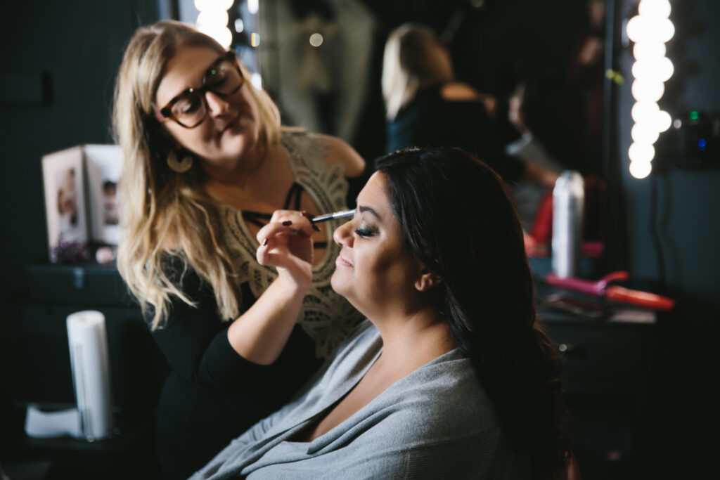 Image of woman receiving hair and makeup for boudoir photography session; Photography by Lindsay Hite 
