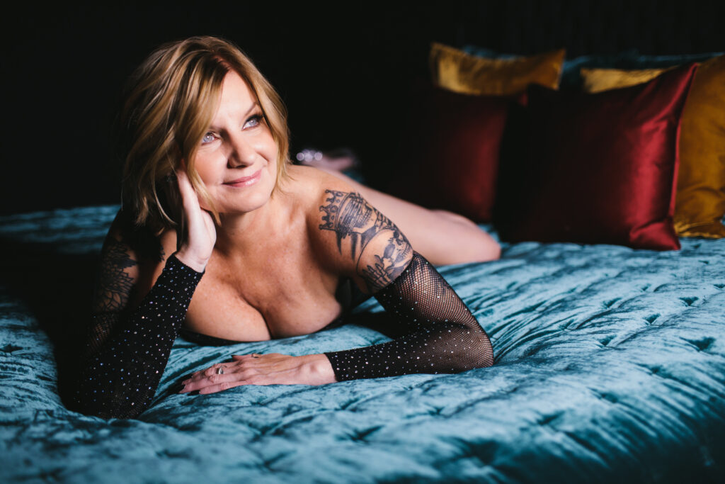 blonde woman posing on her belly on a velvet bedspread, boudoir photography by Lindsay Hite