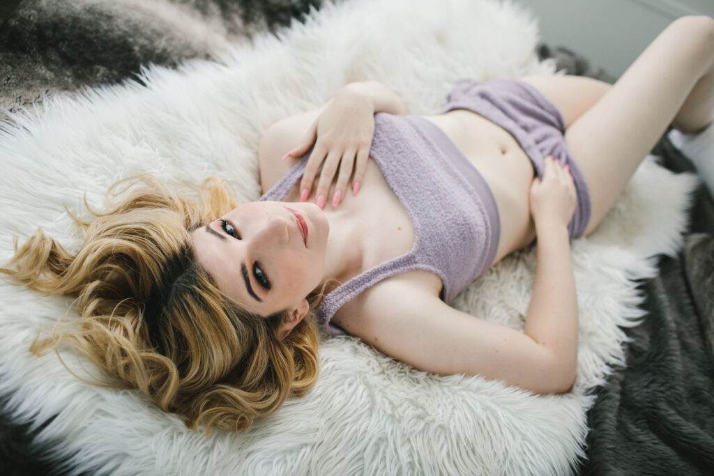 Woman in lavender lingerie laying on her back on fur-lined bed.  Boudoir photography by Lindsay Hite. 