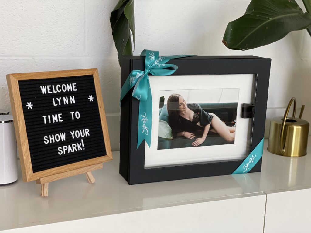 letter board welcoming Lynn to the Show Your Spark studio next to a portrait box featuring her artwork. 