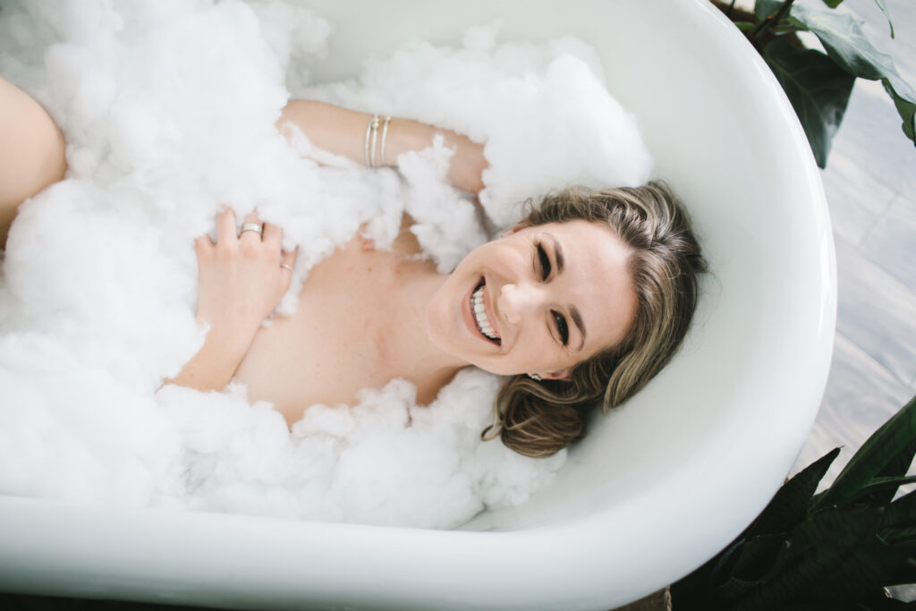 Woman covered in faux bubbles in large white garden tub. Boudoir Photography by Lindsay Hite