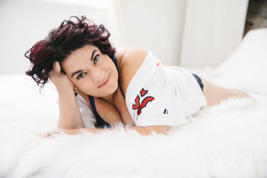 Woman in red socks jersey and navy bra set laying on her belly on a white fur-lined bed.  Photography by Lindsay Hite