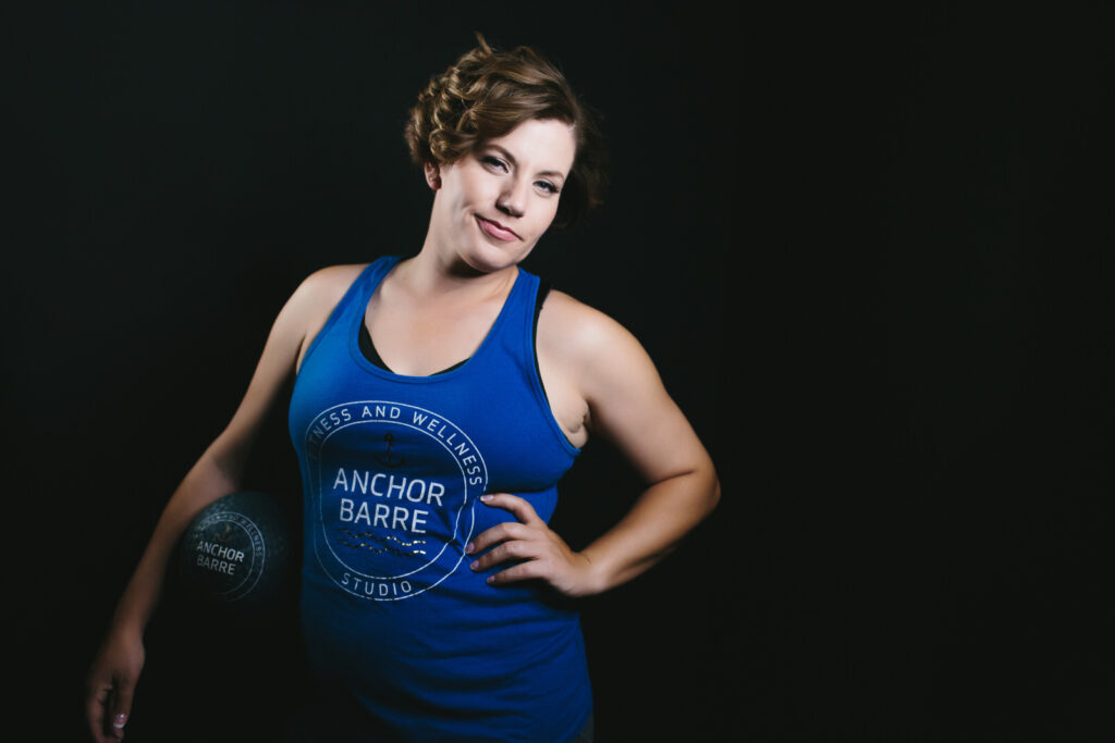 Branding photography of a fitness instructor wearing a blue tank top with a black backdrop.  By Lindsay Hite. 