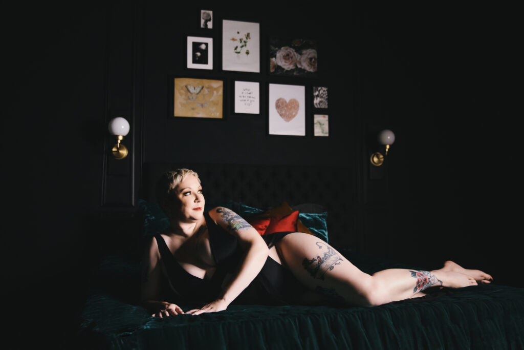 Woman in black lingerie laying on emerald jewel toned bed.  Photography by Lindsay Hite