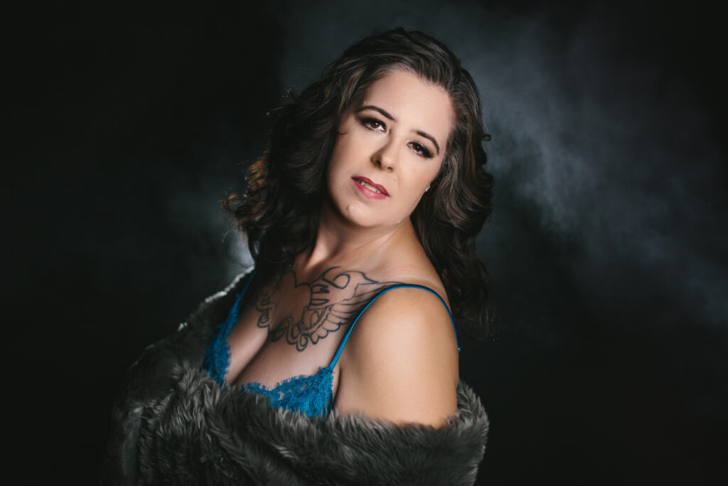 Woman in teal lingerie and fur wrap with a dark backdrop.  Photography by Lindsay Hite