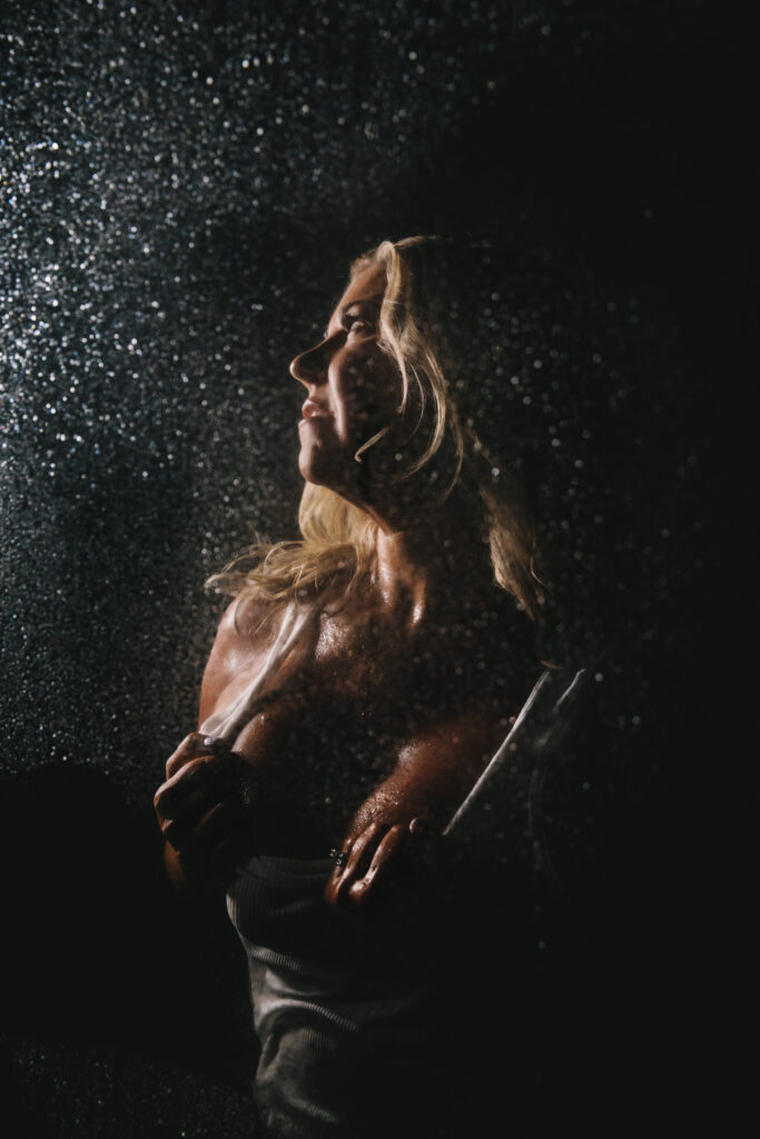 Woman formerly searching for self-acceptance found it through photography by Lindsay Hite. Woman wearing a white t-shirt in a dark shower. 