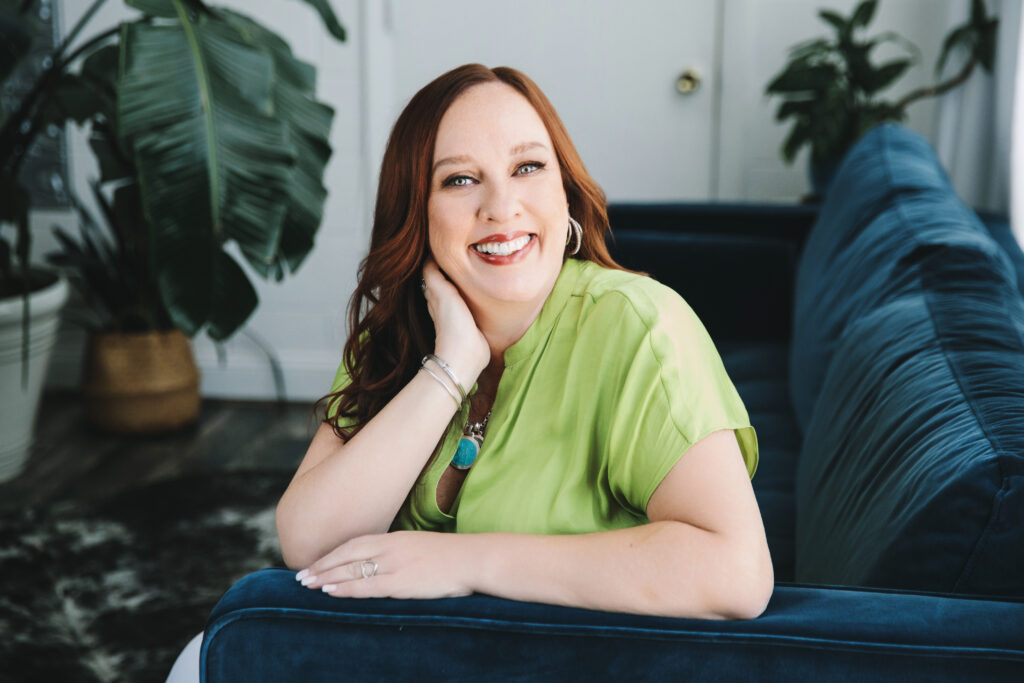 Woman in a branding session portrait sitting on a navy blue sofa with a lime green shirt.  Photography by Lindsay Hite. 