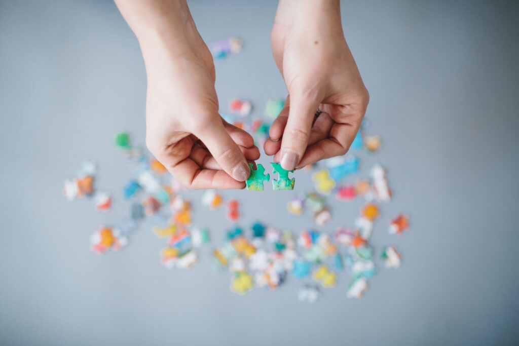 Woman hold puzzle pieces against a white background.  Photography by Lindsay Hite