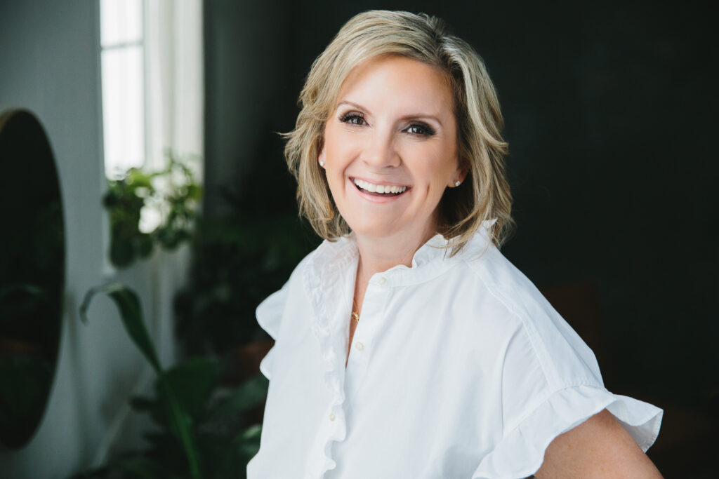 Woman in white blouse smiling at the camera. Photography by Lindsay Hite