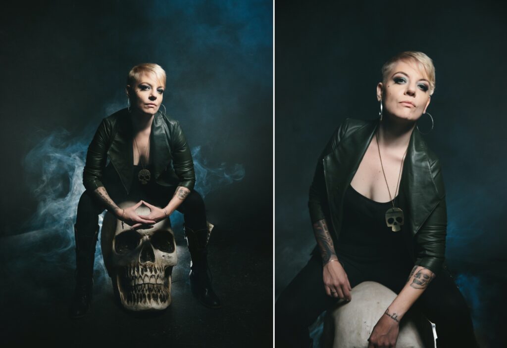 Woman in leather pants and jacket sitting on a large skull with a smokey backdrop.  Photography by Lindsay Hite 