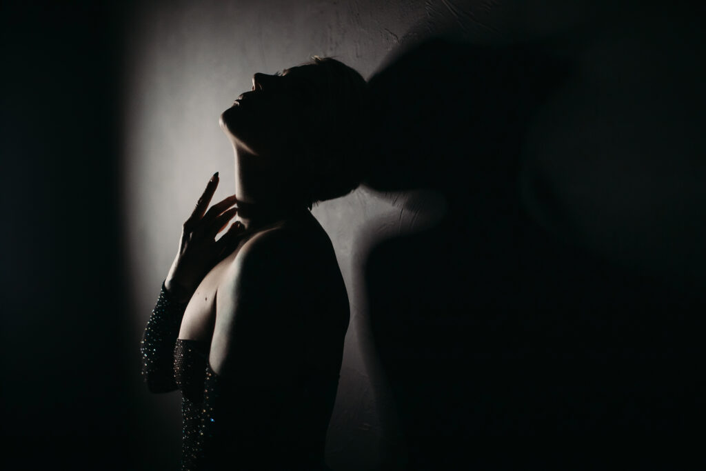 Woman in black rhinestone bodysuit against a black backdrop.  Photography by Lindsay Hite.