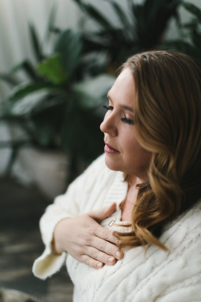 Woman in a meditative movement, wearing a white top. Photography by Lindsay Hite