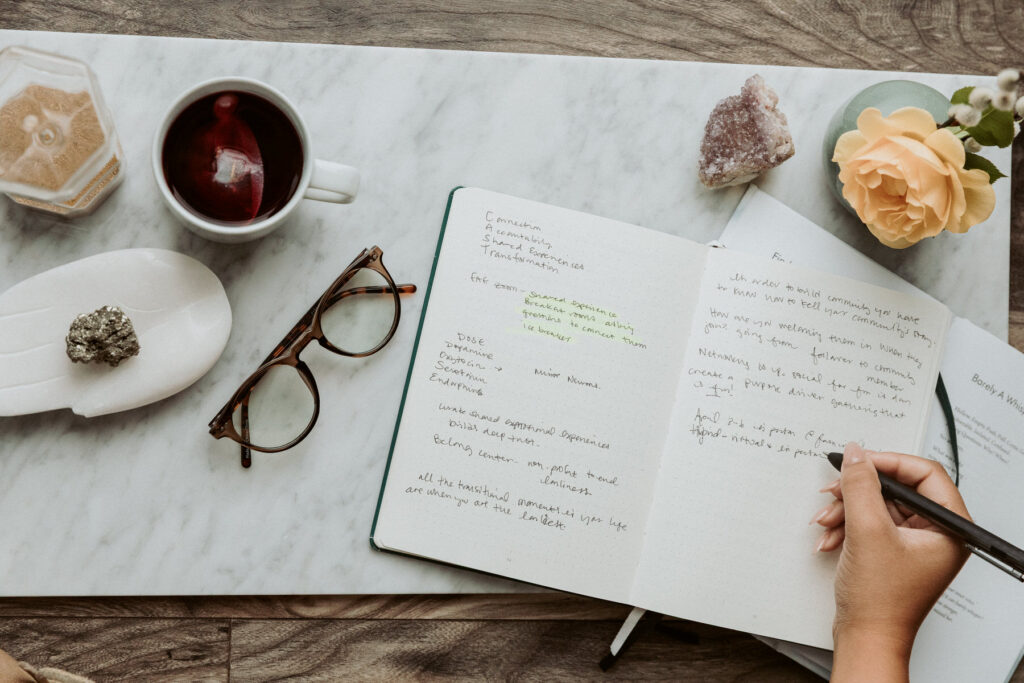 Flat lay of a woman writing in her journal with crystals on the table.
Photography by Lindsay Hite