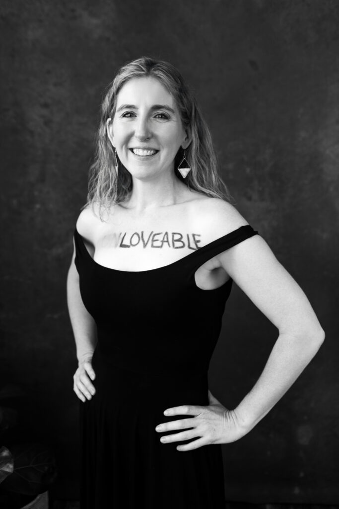 Woman standing in a power pose with the word "loveable" on her chest. Photography by Lindsay Hite. 